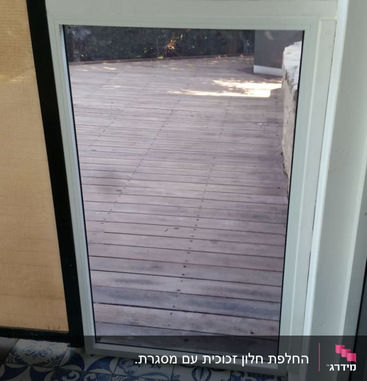 חלון זכוכית עם נוף לחצר עץ